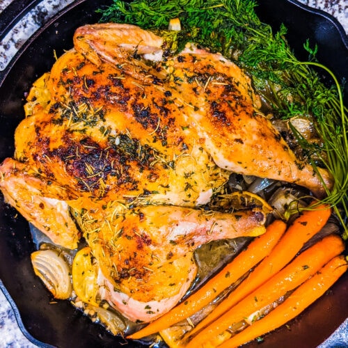 Oven roasted chicken in a cast iron skillet. Sitting by carrots
