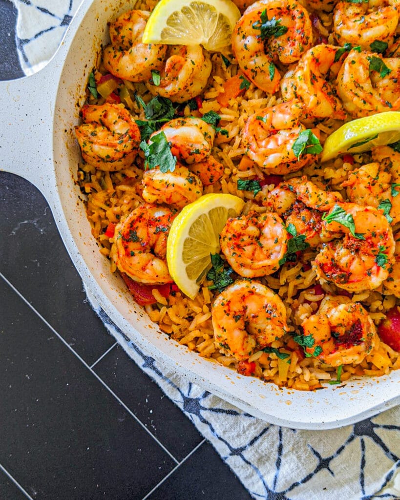 Over head photo of shrimp and rice skillet. with lemons and shrimp on top of the rice