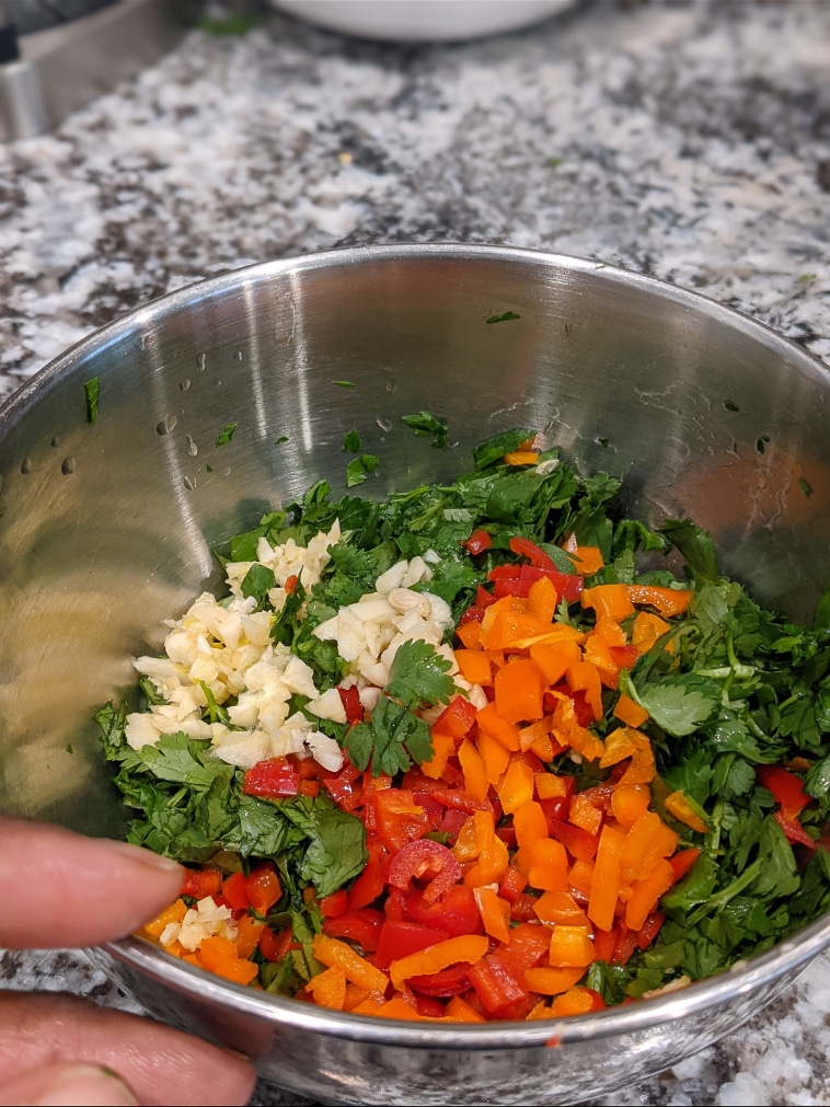 A bowl showing raw ingredients for chimichurri sauce.