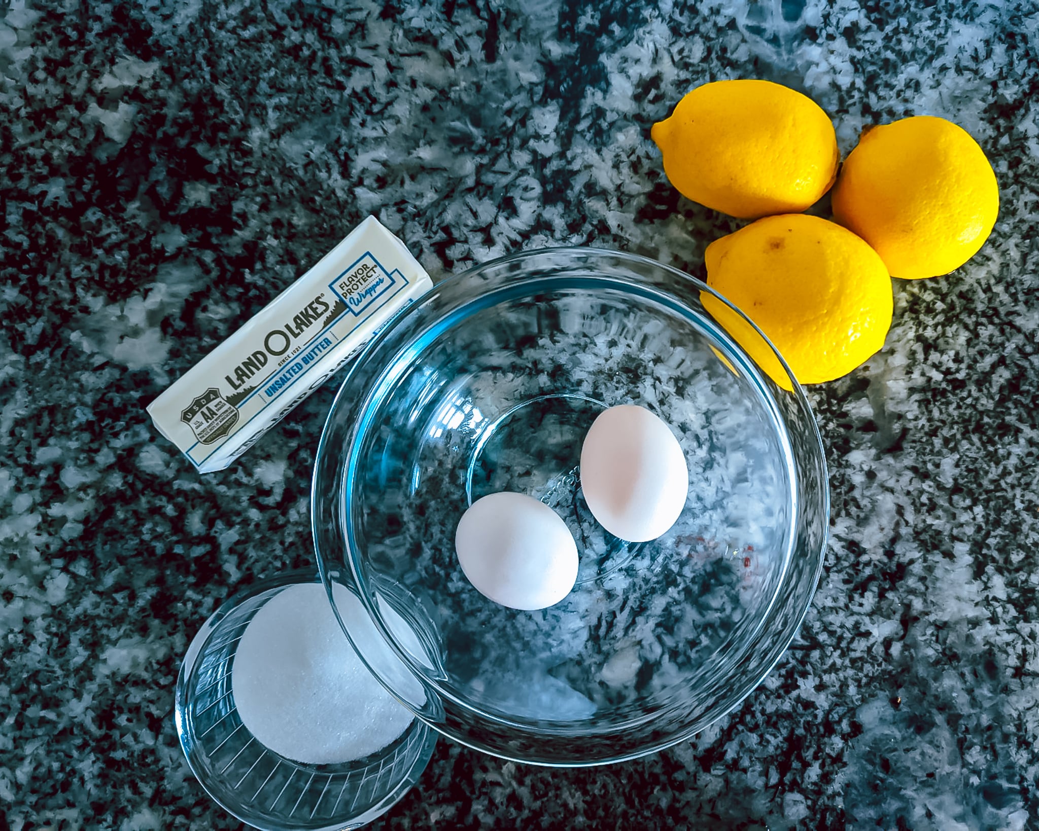 showing ingredients for lemon curd. butter, sugar, eggs, and lemons